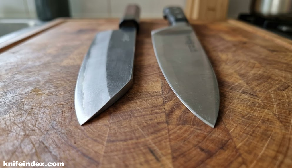 Close-up of a Japanese single bevel knife edge next to a Western double bevel chef knife on a wooden cutting board